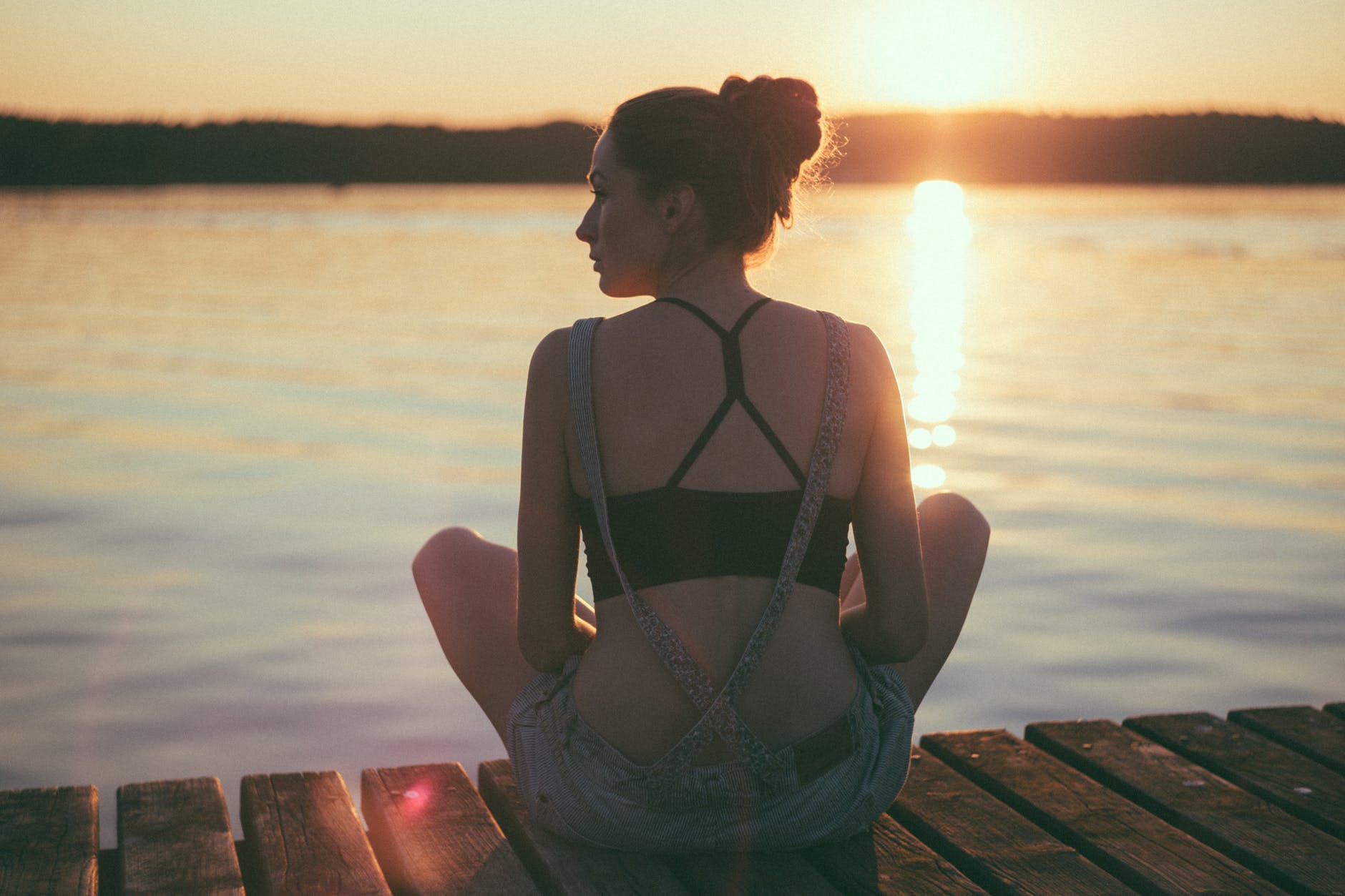 woman siting on dock near large body of water