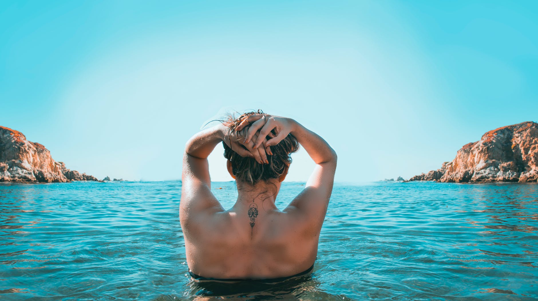 woman on holding her head while standing on body of water