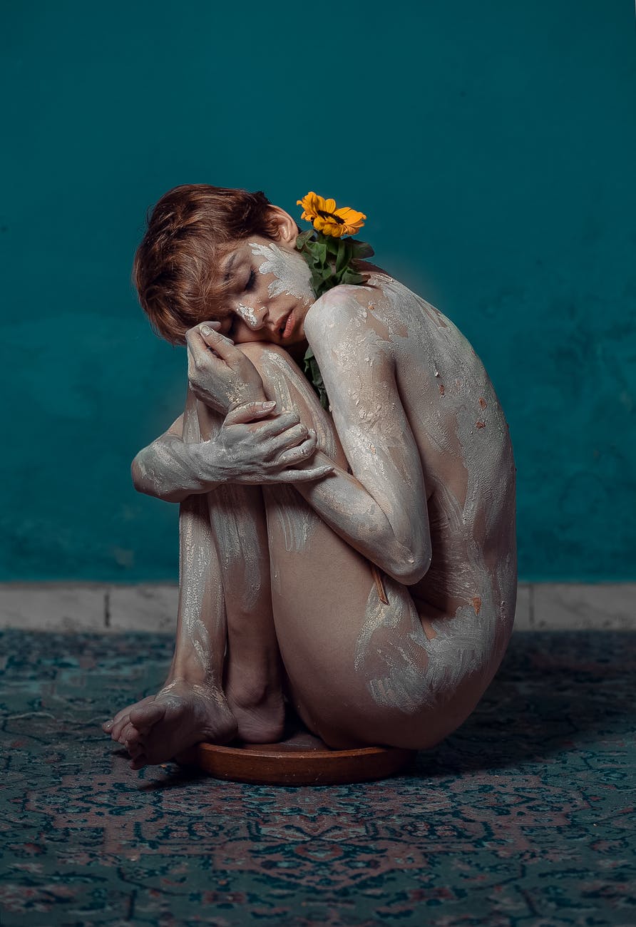 naked woman sitting beside blue wall