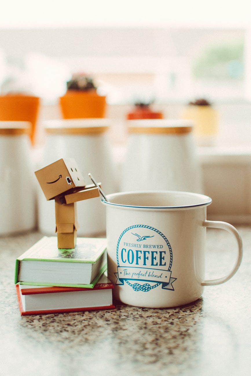 cartoon robot standing on books beside mug