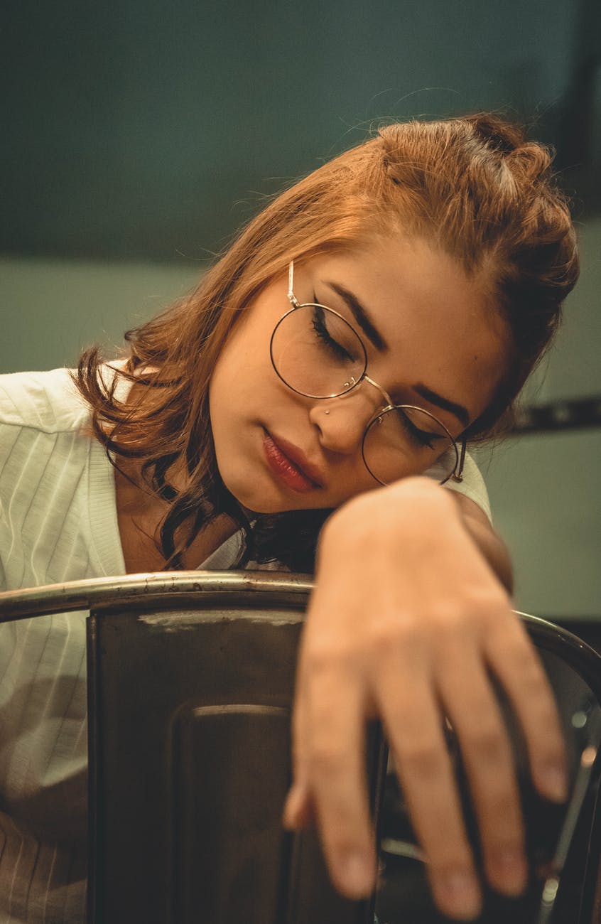 photo of a woman sitting backwards on a metal chair leaning on her arm sleeping