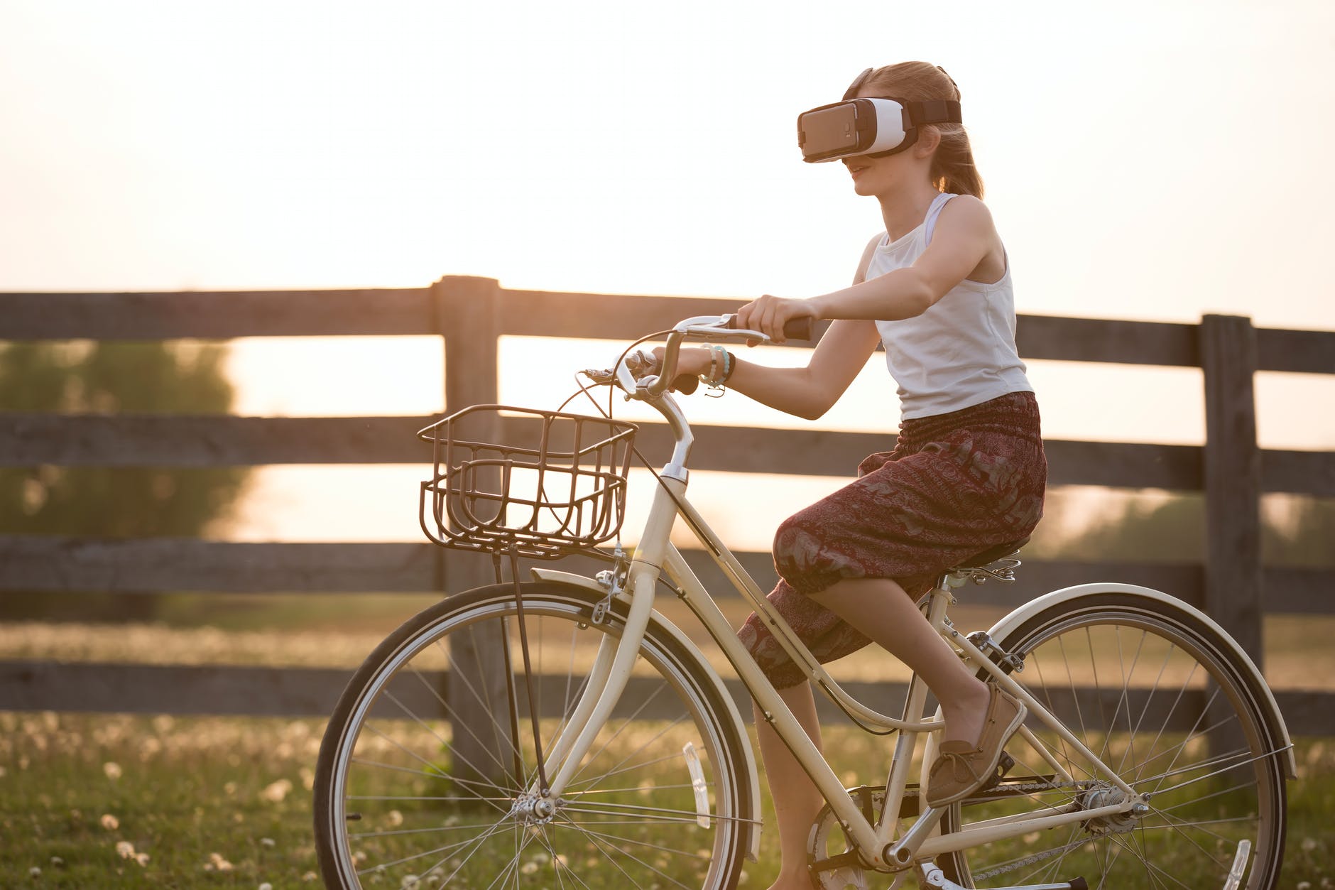 girl wearing vr box driving bicycle during golden hour