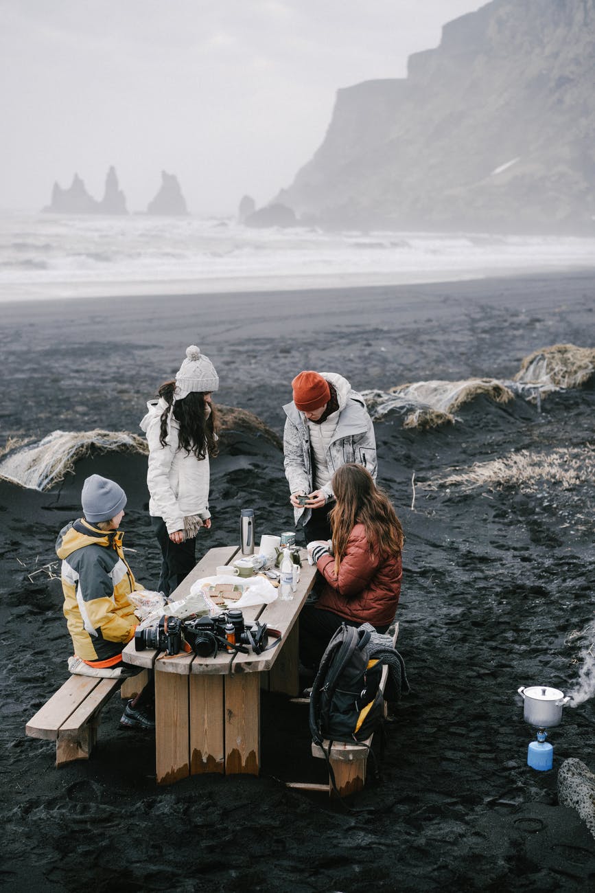 people gathering together on cold sea beach for picnic